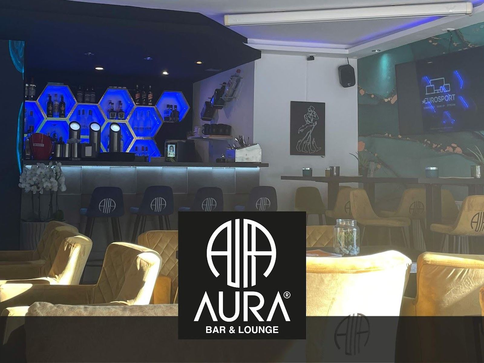 Innenraum der AURA Bar & Lounge mit beleuchteter Wabenwand, Bar und Sesseln